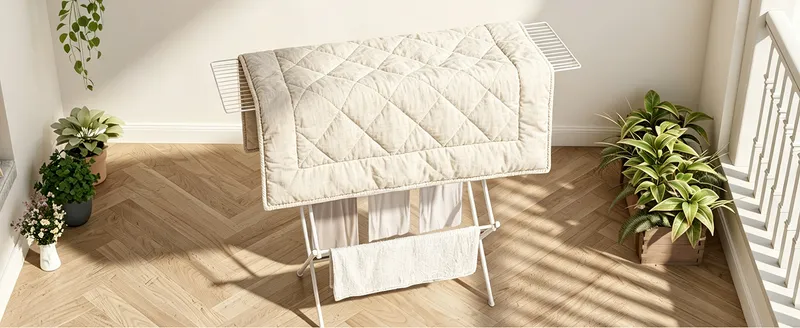 Open drying rack with a quilt over the top rail in a sunlit hallway